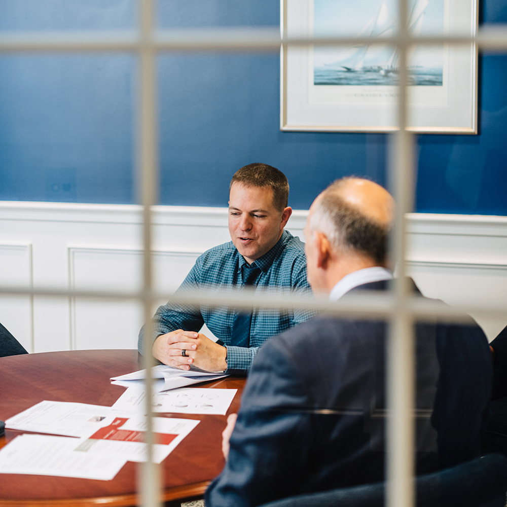 Two men sitting at a table in conversation with papers in front of them