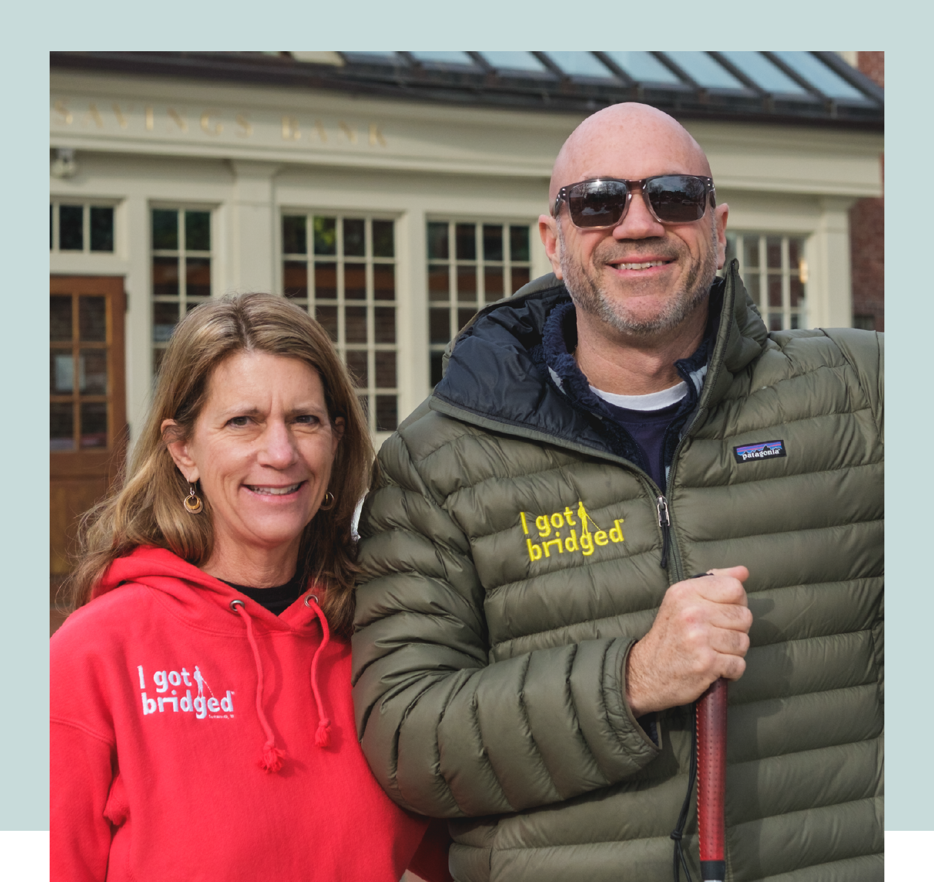 img-here-for-good-campaign-customer-testimonial-freddy-petrone-i-got-bridged photo of man and woman standing in front of building wearing "i got bridged" apparel